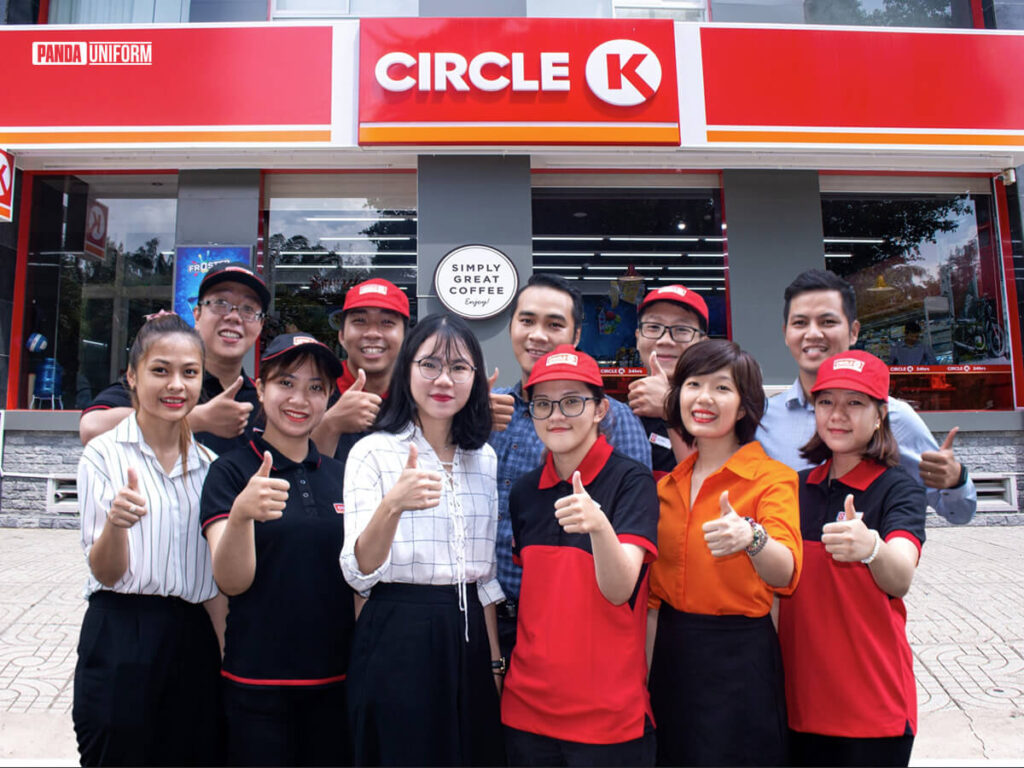 Áo polo đen phối viền đỏ đồng phục Circle K (thứ 2 từ bên trái)